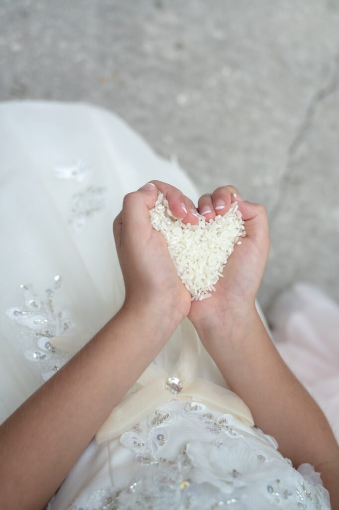 Young girl holding a handful of rice, after the traditional wedding rice shower. Her hands are forming the shape of a heart