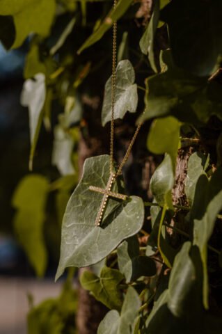 The Christening Cross is hanging from a tree and gently touches an ivy leaf, during a Christening day in Preveza, Greece